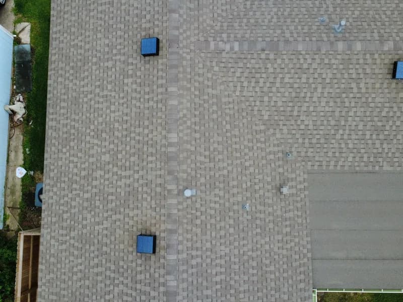 Drone view of a home with a solar attic fan installed mid summer